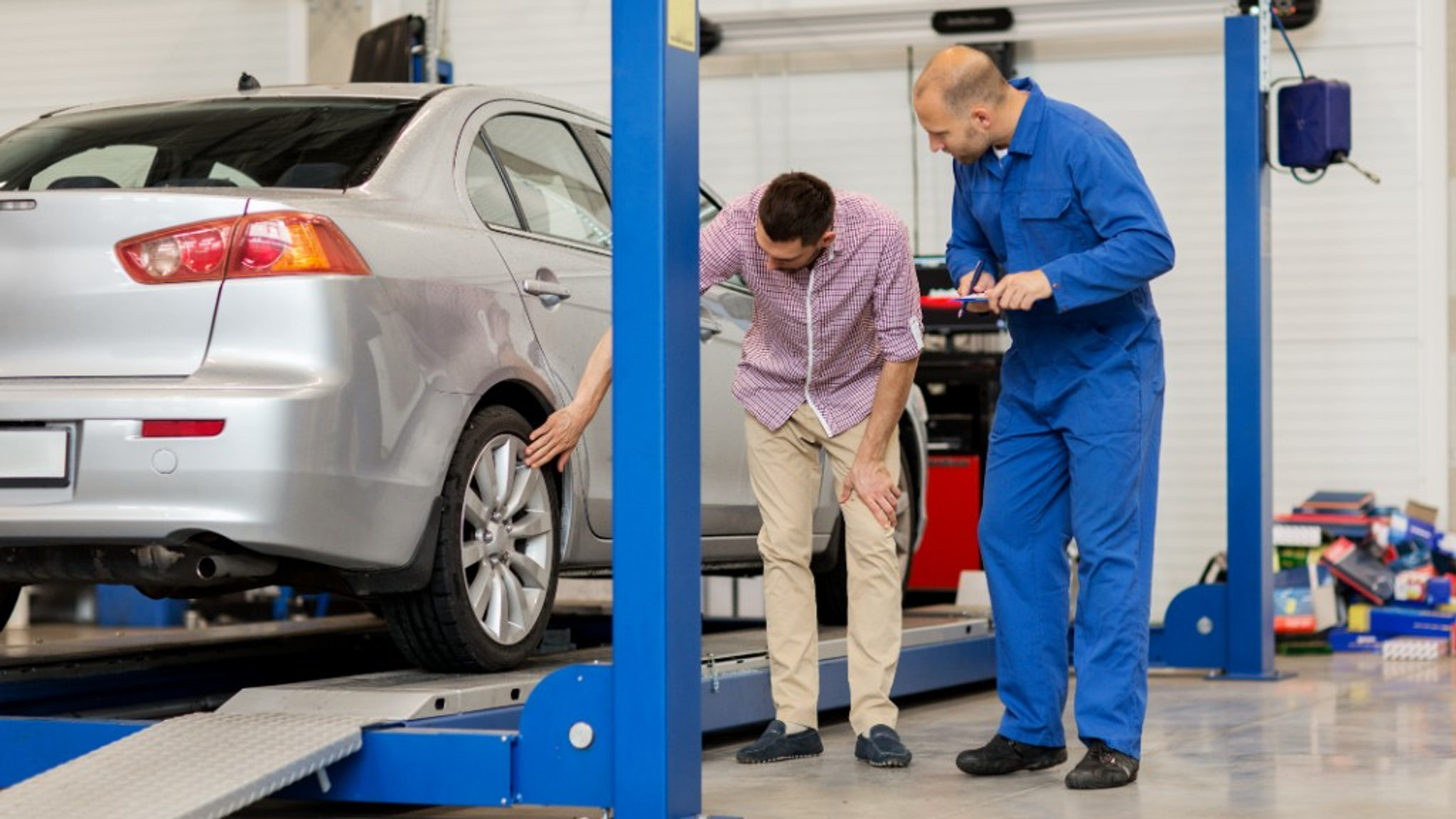 Mechanic and customer discussing work beside a car on a lift at Euro Car Centre